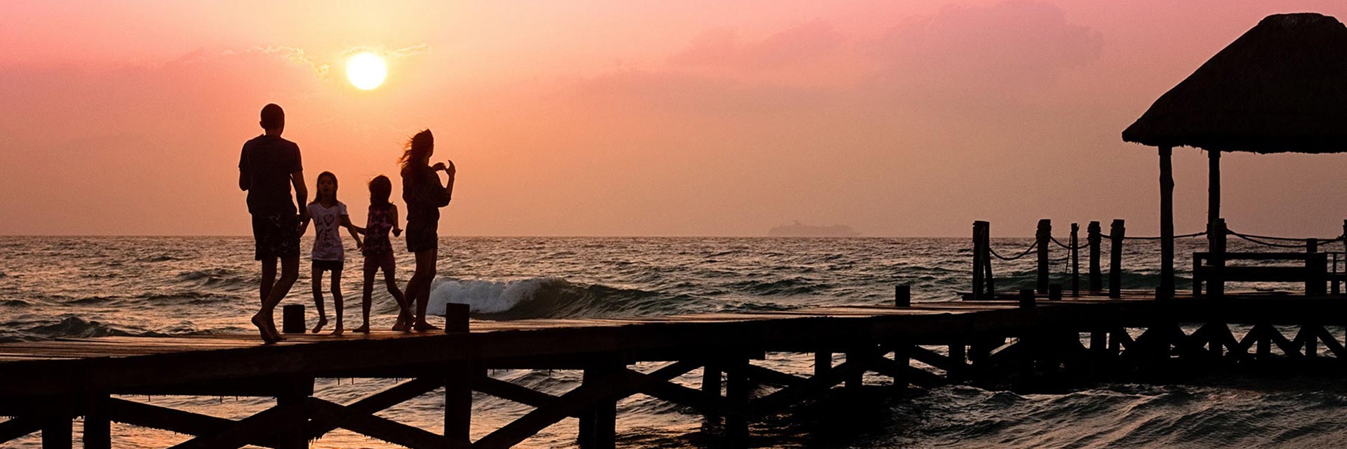 Image of a family standing on a pier looking over at the sunset